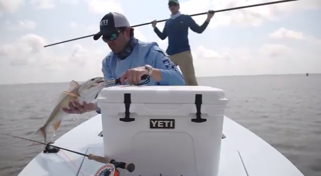 They're putting fish in a white fishing cooler